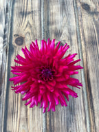 A single bright magenta-pink dahlia flower photographed from above on a rustic weathered wood plank surface.